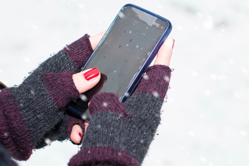 1 female hands holding a cellphone outdoors in the snow